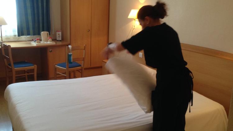 Employé du Groupe SIFU faisant un lit dans une chambre d'hôtel