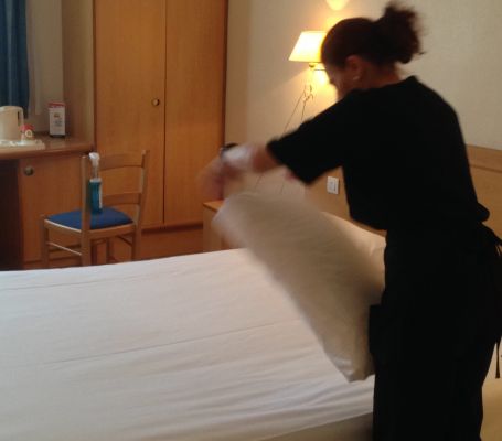 Un employé du Groupe SIFU prépare un lit dans un hôtel