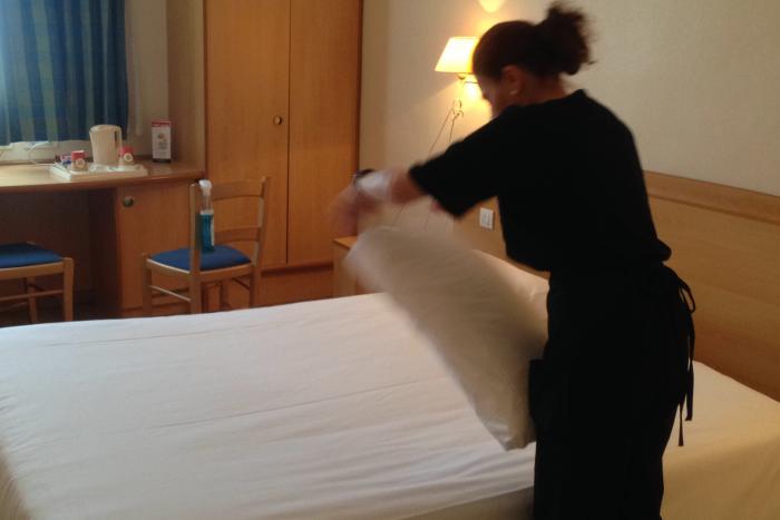 Un employé du Groupe SIFU prépare un lit dans un hôtel
